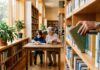 Bibliotecile devin huburi comunitare, dar bibliotecarii rămân printre cei mai prost plătiți Bibliotecar aranjand carti in raft intr-o biblioteca moderna hub comunitar Romania ziua bibliotecarului